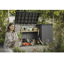 Frau vor einer geöffneten Gerätebox mit Gartengeräten und Rasenmäher