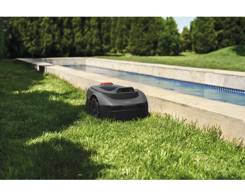 Mähroboter im Garten neben einem Wasserbecken