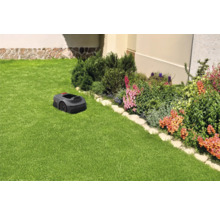 Rasenmähroboter auf einem Rasen neben einem Blumenbeet