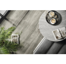 Innenaufnahme eines Raumes mit Holzboden, einem runden Tisch mit Marmorplatte und Dekorationen.