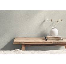 Nahaufnahme einer Wand mit gemusterter Tapete, auf der sich eine Holzbank, Bücher und eine Vase befinden.