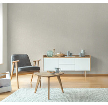 Wohnzimmer mit Sessel, Tisch und Kommode vor einer strukturierten Tapete