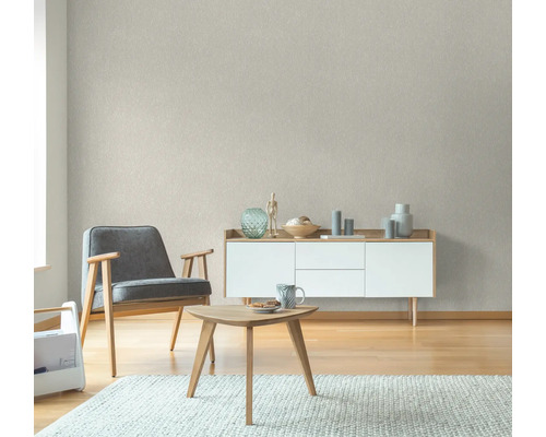 Wohnzimmer mit Sessel, Tisch und Kommode vor einer strukturierten Tapete