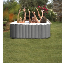 Drei Personen in einem aufblasbaren Whirlpool im Garten, Hände in der Luft