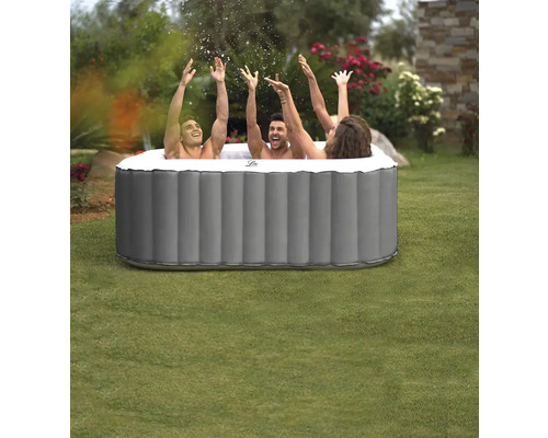 Drei Personen in einem aufblasbaren Whirlpool im Garten, Hände in der Luft