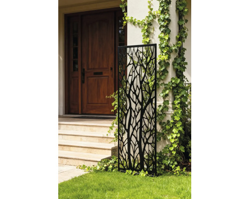 Dekorative Gartenwand mit Baummuster vor einem Haus.