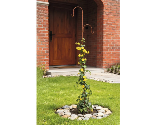 Dekorative Rankhilfe aus Metall mit gelben Blüten im Vorgarten.