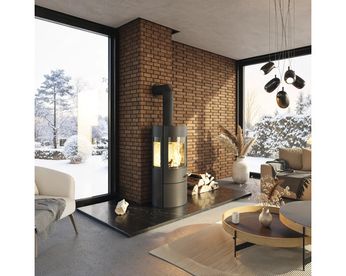 Wohnzimmer mit Kaminofen, Ziegelwand und Fensterblick auf eine verschneite Landschaft