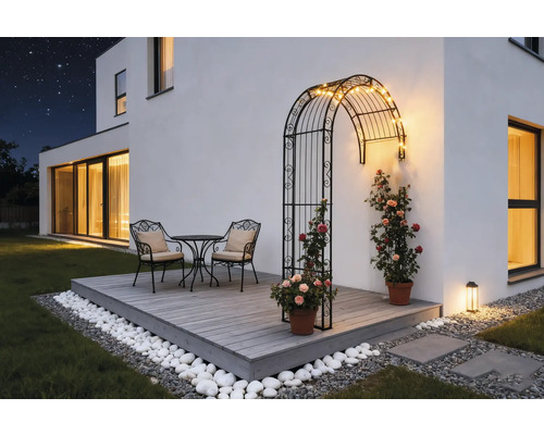 Terrasse mit Rosenbogen, Tischgruppe und Dekoration im Garten