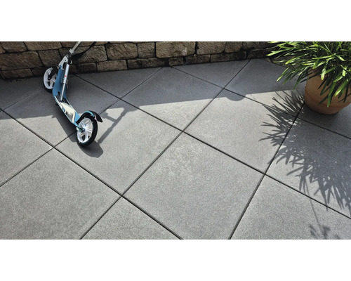 Verlegte Betonsteine im Außenbereich mit Roller und Pflanze