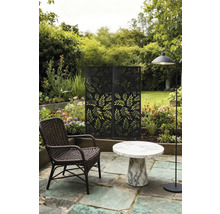 Gartenszene mit Rattan-Sessel, Marmortisch, Stehlampe und Sichtschutz mit Blätterdesign.