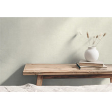 Wohnraum mit Holzbank, Vase und Büchern vor einer hellen Wand