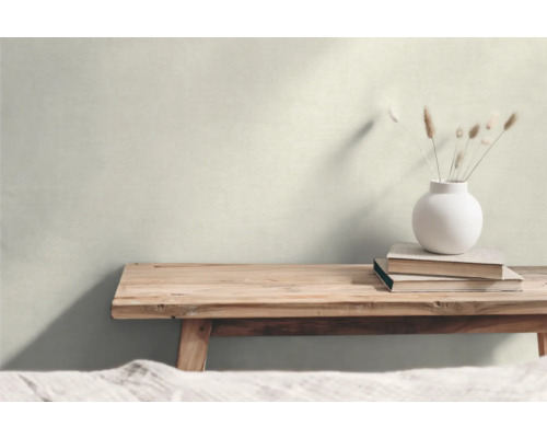 Wohnraum mit Holzbank, Vase und Büchern vor einer hellen Wand