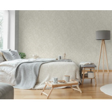 Helles Schlafzimmer mit gemusterter Tapete, Bett, Lampe und Beistelltisch