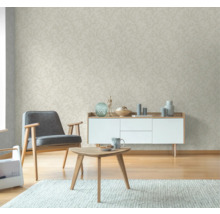Wohnzimmer mit beiger Tapete mit Blattmuster, Sessel, Kommode und Tisch