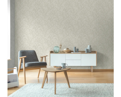 Wohnzimmer mit beiger Tapete mit Blattmuster, Sessel, Kommode und Tisch