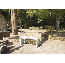 Gartenansicht mit Steinbrunnen und einer weißen Bank