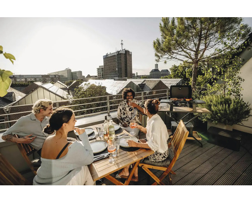 Personen grillen und essen auf einer Dachterrasse mit Stadtblick