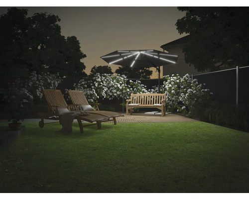 Garten mit Liegestühlen, Bank und beleuchtetem Sonnenschirm bei Dämmerung