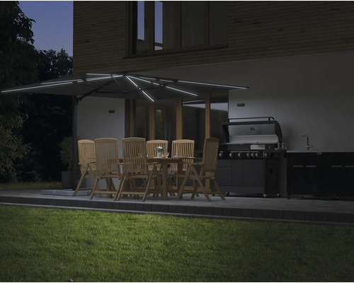 Beleuchteter Gartensitzplatz mit Sonnenschirm, Tisch, Stühlen und Grill