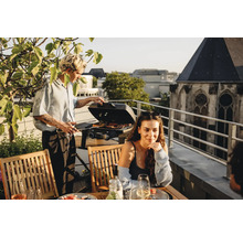 Szene auf einer Dachterrasse mit Personen beim Grillen mit einem Gasgrill.