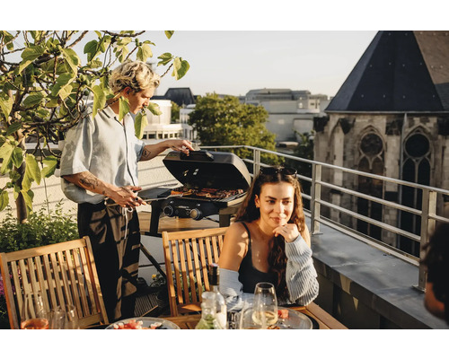 Szene auf einer Dachterrasse mit Personen beim Grillen mit einem Gasgrill.