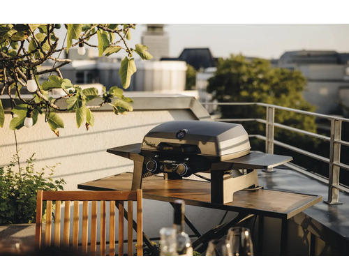 Gasgrill auf einem Balkon mit einem Holztisch und Stühlen