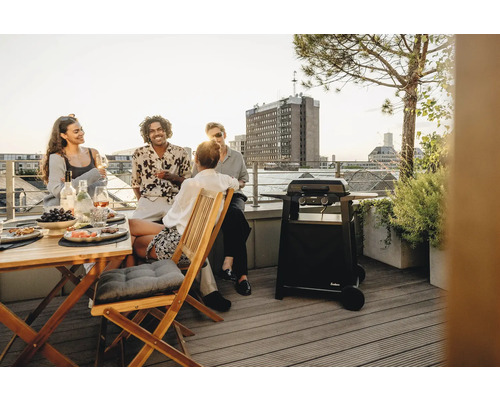 Gruppe von Personen grillt auf einer Dachterrasse mit einem Enders Gasgrill.