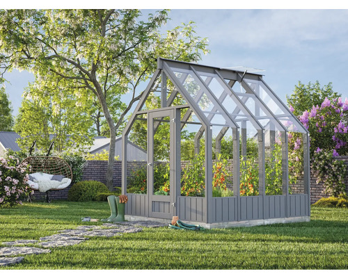 Gewächshaus im Garten mit Tomatenpflanzen und Gartenzubehör