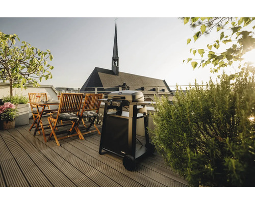 Terrasse mit Grill, Holztisch und Stühlen vor dem Hintergrund einer Kirche