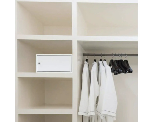 Einbauschrank mit einer darin integrierten Medikamentenbox, Kleidung und Kleiderbügel.