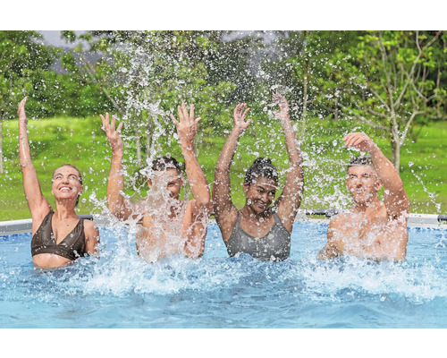 Vier Personen planschen in einem Swimmingpool und werfen Wasser in die Luft.