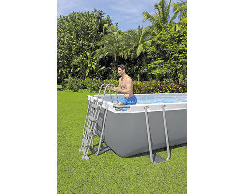 Mann steigt über eine Leiter in einen rechteckigen Stahlrahmenpool im Garten