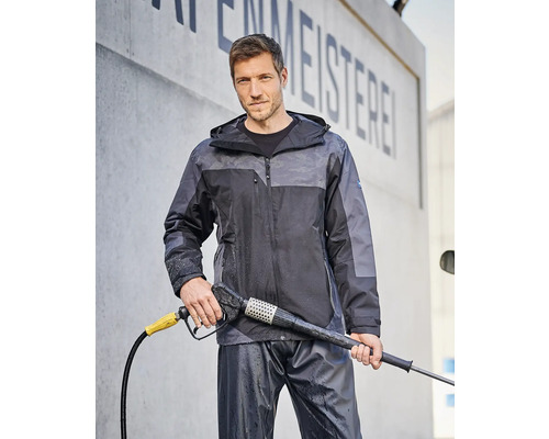 Mann mit Hochdruckreiniger und wasserdichter Jacke und Hose