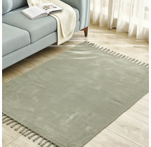 Quadratischer Teppich mit Fransen neben einem Sofa auf einem Holzboden