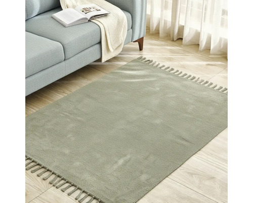 Quadratischer Teppich mit Fransen neben einem Sofa auf einem Holzboden