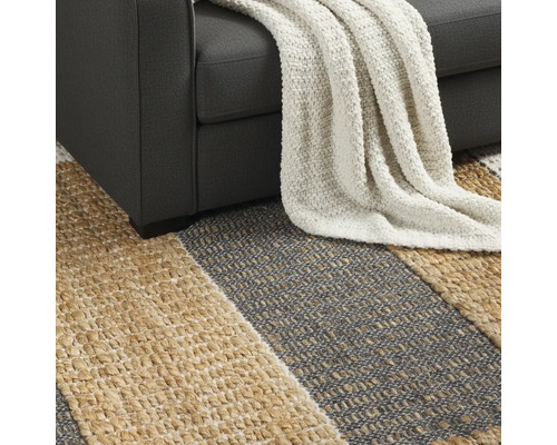 Detailansicht eines gestreiften Teppichs unter einem Sofa mit einer Decke.