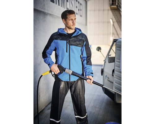 Mann mit Hochdruckreiniger, gekleidet in einer wasserdichten Jacke und Hose.