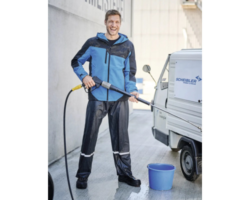 Mann mit Hochdruckreiniger, Arbeitshose und Arbeitsjacke reinigt Transporter