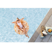 Frau entspannt sich auf einem Schwimmring im Pool, mit Handtüchern und Getränken am Beckenrand