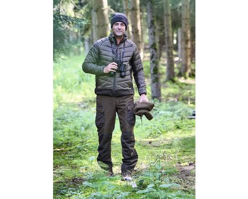 Mann mit Fernglas, Steppjacke, Mütze und Hose im Wald