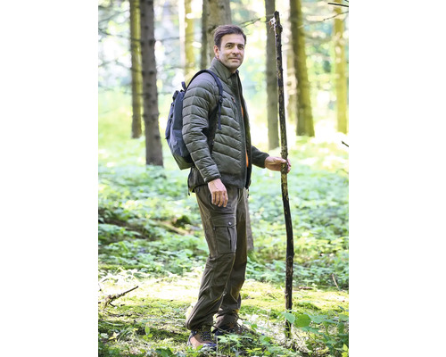 Mann mit Rucksack, Stecken, Steppjacke und Cargohose im Wald