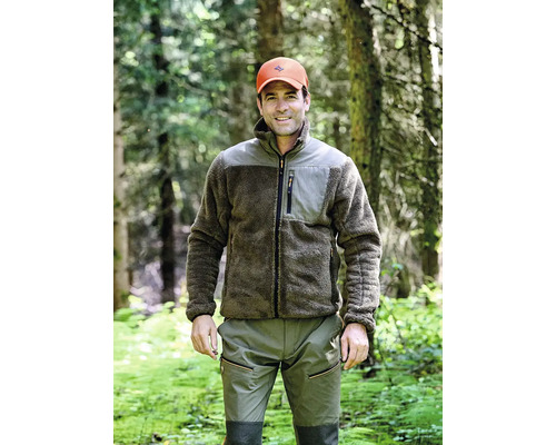 Mann in Fleecejacke und Hose im Wald.