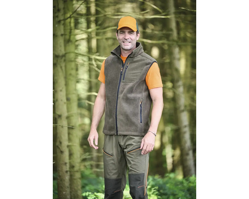 Mann in Fleeceweste, Hose und Kappe im Wald