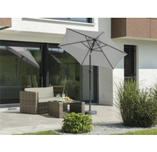 Gartenszene mit Sonnenschirm, Loungemöbeln und Dekoration auf der Terrasse