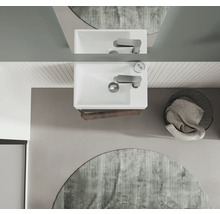 Draufsicht eines Badezimmers mit Waschbecken, Armatur, Spiegel, rundem Teppich und Wäschekorb