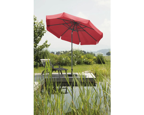 Roter Sonnenschirm neben einem Liegestuhl auf einer Holzterrasse am See