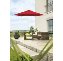 Gartenszene mit rotem Sonnenschirm, Rattanmöbeln und Pflanzkübel auf einer Terrasse