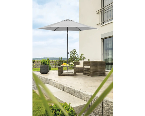 Gartenszene mit Sonnenschirm, Rattansesseln und Tisch auf einer Terrasse