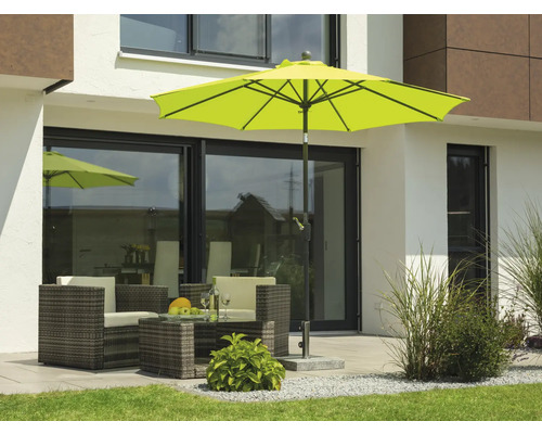 Szene mit Gartensitzgruppe unter einem Sonnenschirm auf einer Terrasse vor einem Haus.